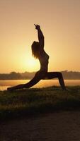 A tranquil silhouette beautifully captured during a serene morning yoga session by the water, symbolizing a deep sense of tranquility and harmony with the surrounding nature and environment video