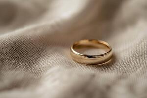 Golden wedding ring resting on soft white fabric photo