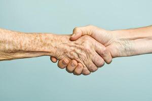 Young and old hand shaking showing generational differences photo