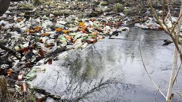Dirty river is polluted with many plastic bottles. A lot of trash is dumped in open and freely available places at nature. Global environmental pollution problem. Concept of ecological disaste video