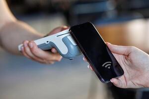Customer paying via smartphone using NFC contactless payment technology at retail checkout. photo