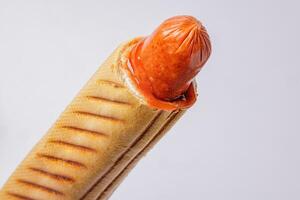 Hot dog in crispy bread roll with ketchup, isolated on white background, detailed close-up view. photo