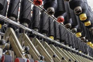 Black yarn cones on industrial textile machinery in a modern spinning or weaving factory. photo