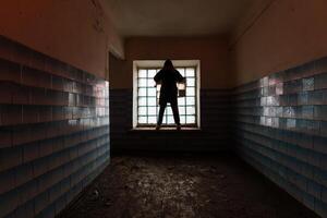 Man silhouette in abandoned building with block glass window photo