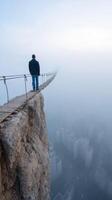 man stands on narrow bridge above foggy cityscape photo