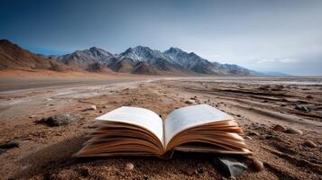 open book lies on desert landscape with mountains in background photo