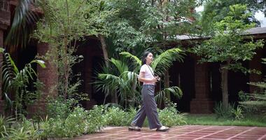 Handheld shot, Solo female tourist enjoys taking photos with camera while taking a leisurely stroll amidst serene surroundings and the cultural richness of the place. video