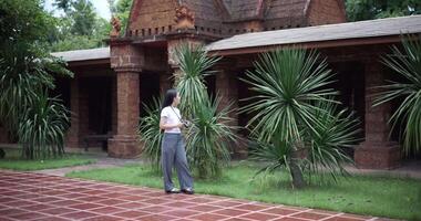 Solo female tourist enjoying taking photos with camera while taking a leisurely stroll amidst serene surroundings and the cultural richness of the place. video