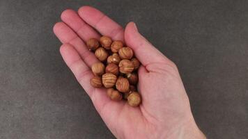 A hand holding a handful of nuts on a gray background video