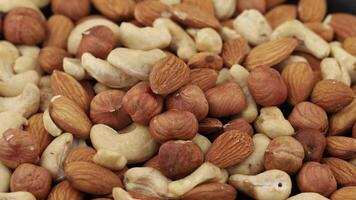 Mixed nuts assortment featuring almonds, cashews, and hazelnuts displayed on a dark surface video