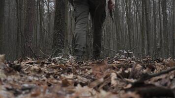 Man Walking Through Forest Ground Covered in Leaves, Close-up of boots stepping on fallen leaves in a misty, cold forest during late autumn. video
