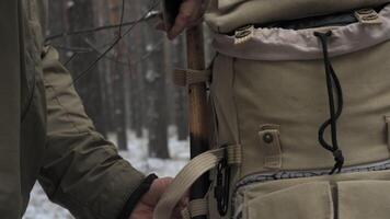 Bushcraft adventure in winter forest, Close-up of a person holding an axe next to a rugged backpack, standing in a snowy forest, ready for a bushcraft adventure. video