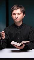 vertical Priest praying with rosary and holy book at table video