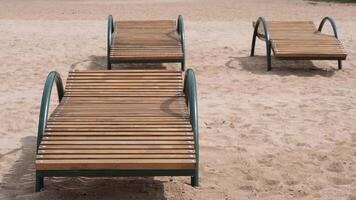 Wooden sunbeds standing on sandy beach inviting tourists to relax video