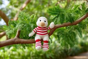 White plush monkey with red and white striped sweater and socks sitting on a tree branch photo