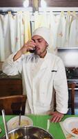 hombre en vestido como un cocinero bebidas nuevo rojo vino a su hogar video