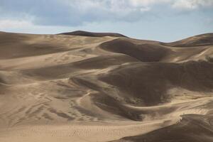 Waves of sand create intricate patterns in a desert landscape under a bright sky photo