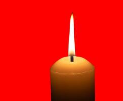 A yellow burning candle isolated on red background with clipping path photo