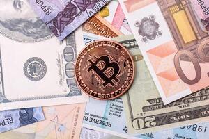 Bitcoin on a background of paper banknotes of different currencies photo