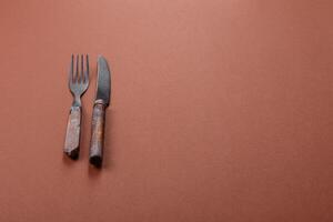Knife and fork on a brown table photo