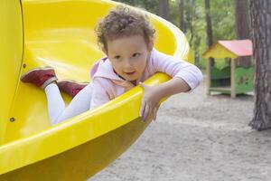 A sweet little child with curly hair on the playground photo
