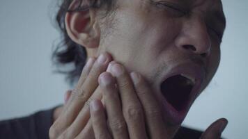 a close up of a man suffering from a toothache, he holds his cheek in pain, expressing discomfort video