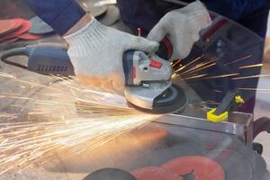 Mechanic using angle grinder and working with metal in workshop photo