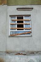 A boarded-up plastic window in an old, abandoned, crumbling building photo