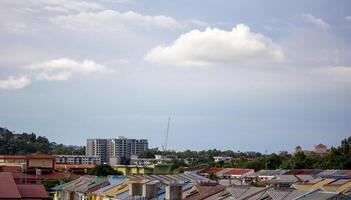 Urban residential rooftops beneath a clear blue sky with soft white clouds in peaceful daytime setting photo
