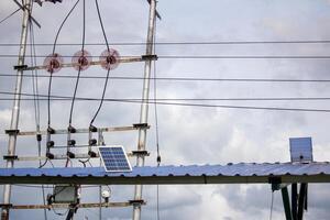 High voltage power lines and solar panels on a structure under a cloudy sky, symbolizing renewable and electrical energy integration photo