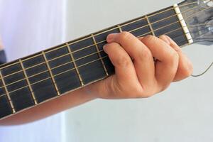 A close-up shot of a hand pressing strings on a guitar fretboard, showing finger placement and technique in detail photo