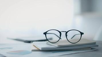 Glasses sit atop a stack of documents, symbolizing focus and productivity in a modern corporate office. A coworking environment promotes collaboration and professional growth. video