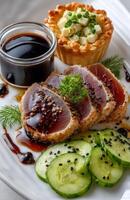 Tuna fillet with honey sauce, oval quiche, cucumber side dish on white plate photo