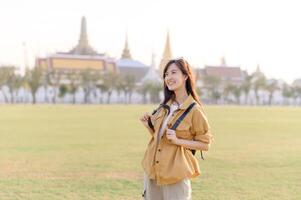 Asian woman tourist in thailand with backpack and backpack in front of the buddhist temple photo