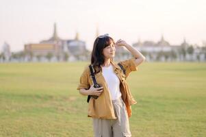 Asian woman in yellow jacket standing in grass with a building in background photo
