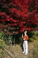 A woman standing in front of a red tree photo
