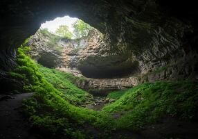 A cave with a green grassy area inside photo