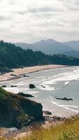 Cannon Beach Coastal cliffs and sandy beach with ocean waves. A scenic coastal landscape with rocky cliffs and a long sandy beach, where gentle ocean waves meet the shore. video