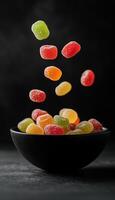 Jelly candies colorful fruity flavor floating, black ceramic bowl in story background photo