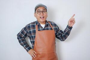 Asian barista man wearing apron and cap showing and pointing up with fingers number one while smiling confident and happy over white background photo