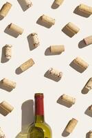 Frame from wine corks, vintage corkscrew and red wine bottle on beige background with shadows at sunlight. Minimal style layout with bottle cork, bottle opener, design concept for wine list photo