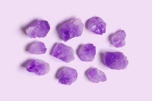 Flatlay purple amethyst crystals on violet color background. Amethyst stone magic and healing crystal, alternative medicine. Top view natural gemstone rocks, quartz mineral, monochrome pattern photo
