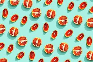 Red orange fruit as bring summer food pattern, slices of citrus with hard shadows at sunlight on mint background. Healthy fruits food concept. Flat lay with juicy red orange, creative layout photo