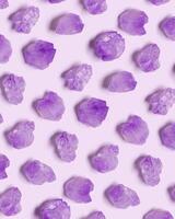 Creative pattern of purple amethyst crystals on very peri color background, top view natural beautiful gemstone as geometric layout. Amethyst stone healing crystal, precious gem, flat lay photo