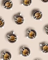 Pattern with black coffee cups, drip coffee bag with ground coffee for brewing in cup, paper bag drip coffee filter, beige background, top view, minimal trend flat lay photo