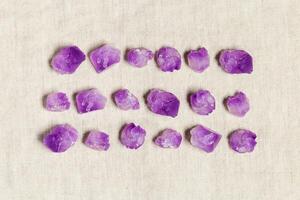 Square pattern of purple amethyst crystals on textile background, top view natural beautiful gemstone as geometric layout. Amethyst stone healing crystal, flat lay photo