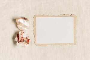 Empty Invitation card, blank card with protection crystal, healing stone quartz on fabric background tablecloth. Torn craft paper with copy space for text, top view mock up paper postcard photo