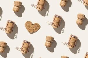 Creative pattern with champagne cork and heart on beige background with hard light and shadows at sunlight. Champagne love concept, bottle cap from sparkling wine and metal wire muselet photo