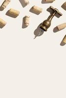 Background with wine corks and old bottle opener for white and red wine on beige pastel color with shadow at sunlight, copy space. Trend layout with bottle wood cork and corkscrew, top view table photo