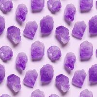 Flat lay purple amethyst crystals on violet color background. Amethyst stone magic and healing crystal, alternative medicine concept. Top view natural gemstone rock, seamless pattern photo